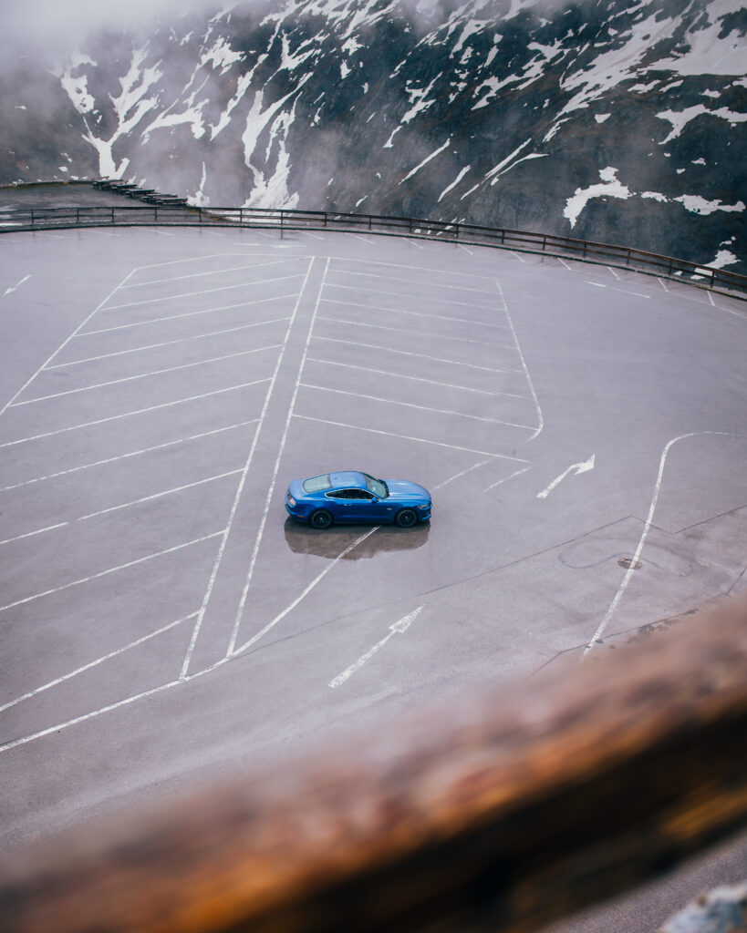 Blauer Mustang allein auf einem leeren Parkplatz, aus großer Höhe fotografiert.