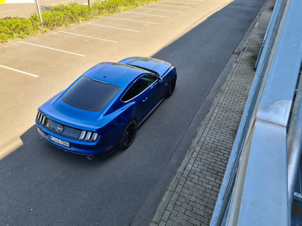 Blauer Mustang allein auf einem leeren Parkplatz.