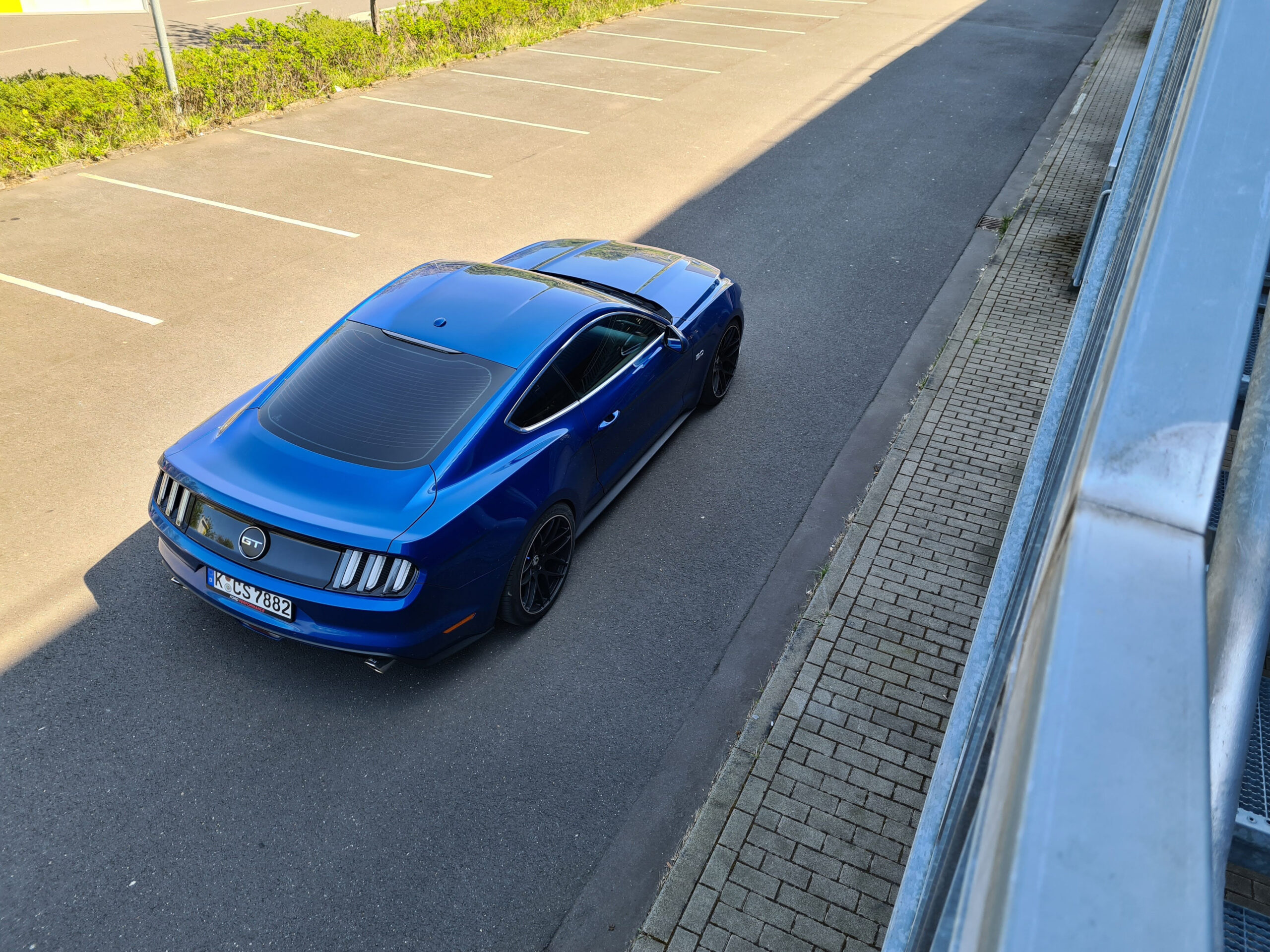Blauer Mustang allein auf einem leeren Parkplatz.