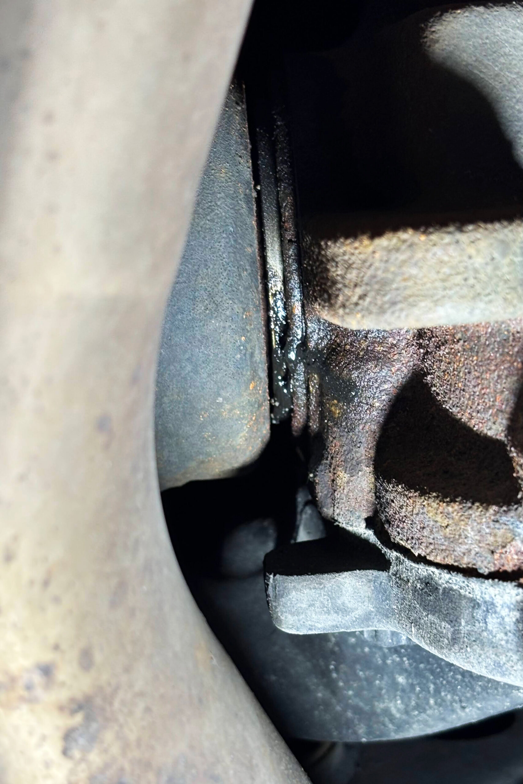 Nahaufnahme von angesammeltem dickem Öl an der Dichtung zwischen Antriebswelle und Differential bei einem Mustang GT